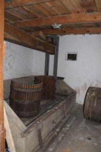 Traditionelle Weinkelter in rustikalem Keller, ein Zeugnis regionaler Handwerkskunst für Prima Magazin.