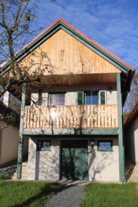 Modernes, zweistöckiges Holzhaus mit grünem Dach in sonniger, ländlicher Umgebung – ideal für das Prima Magazin.