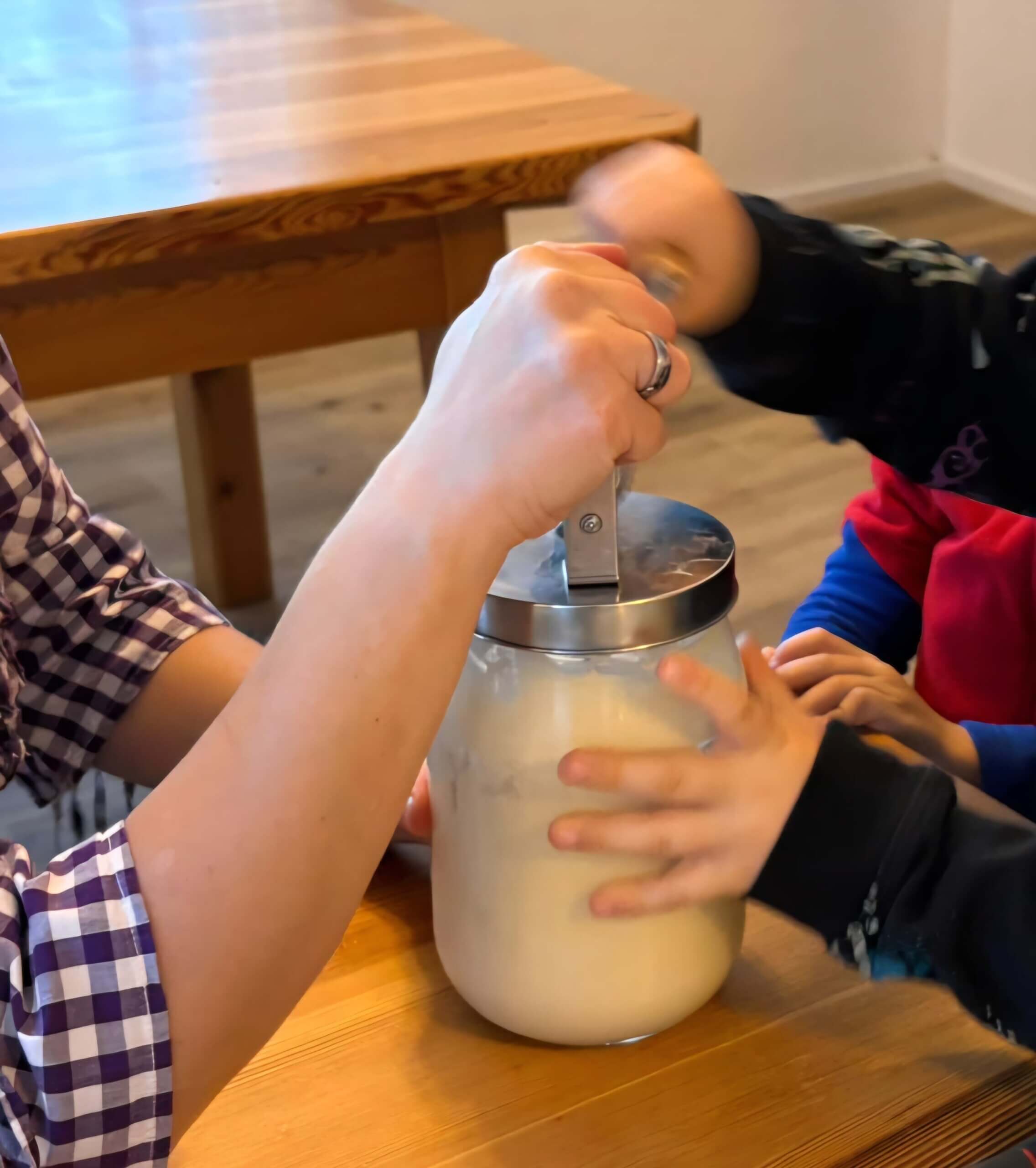 Erwachsene und Kind bereiten gemeinsam hausgemachte Butter in einem Glas zu, als Teil eines Artikels in Prima Magazin.