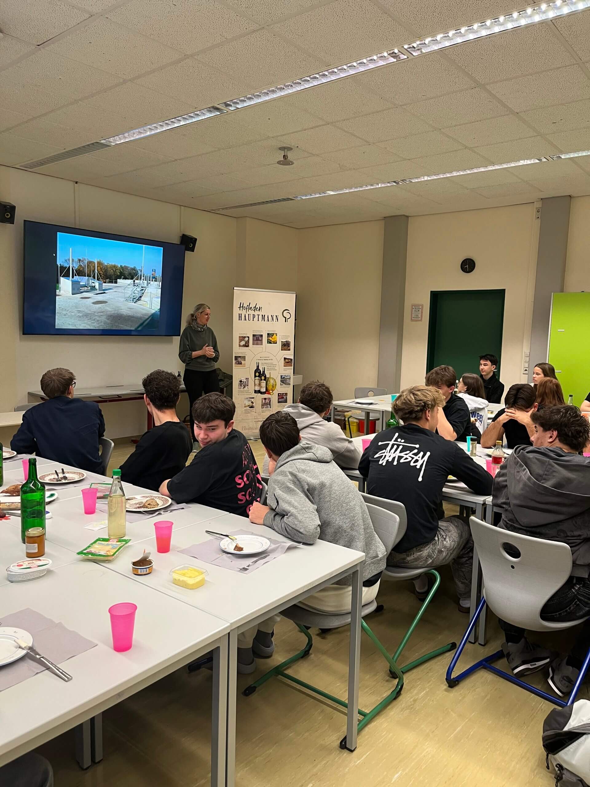 Junge Erwachsene bei einem interaktiven Vortrag in einem Klassenzimmer, fokussiert an einer Präsentation teilnehmend.
