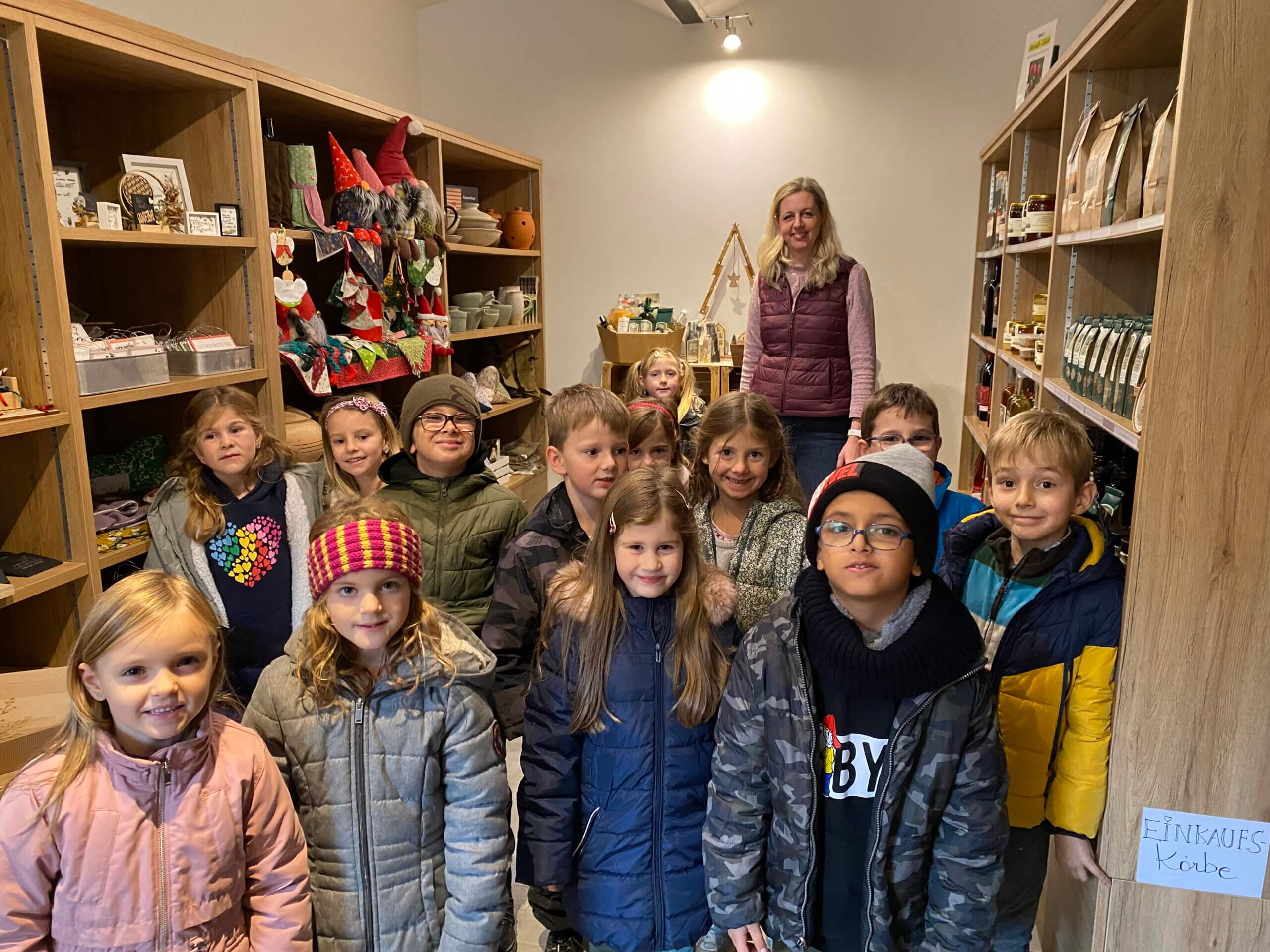 Gruppe von Kindern erkundet einen lokalen Laden mit regionalen Produkten, betreut von einer Frau. Perfekt für Prima Magazin.