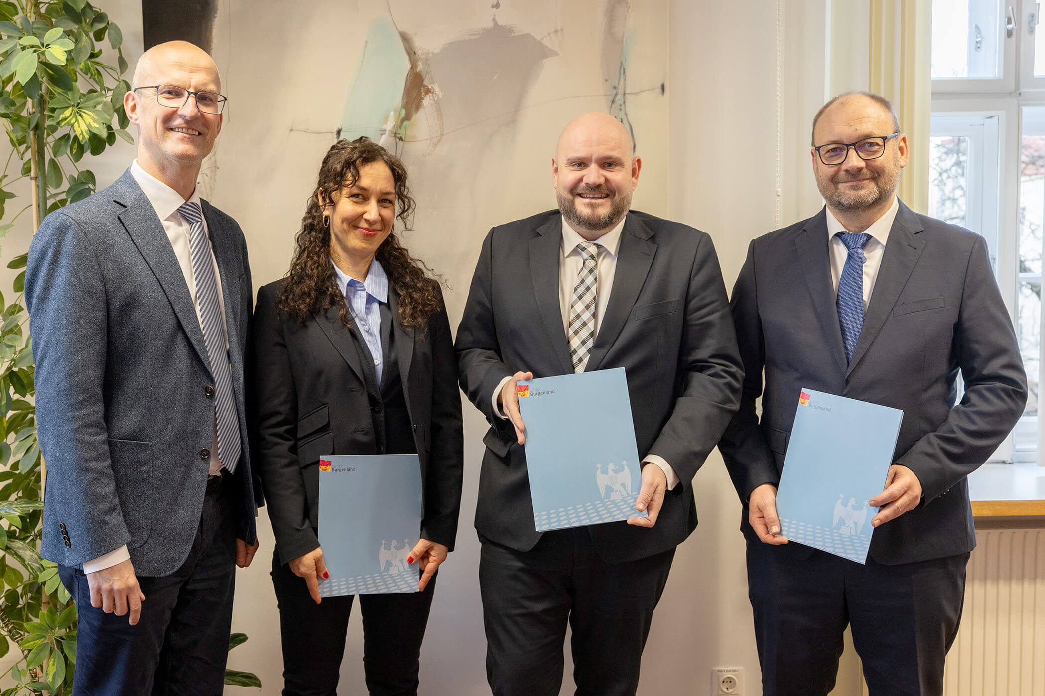 Vier Personen in Businesskleidung präsentieren Dokumente in einem Büro. Event für qualitätsorientierten Regionaljournalismus.