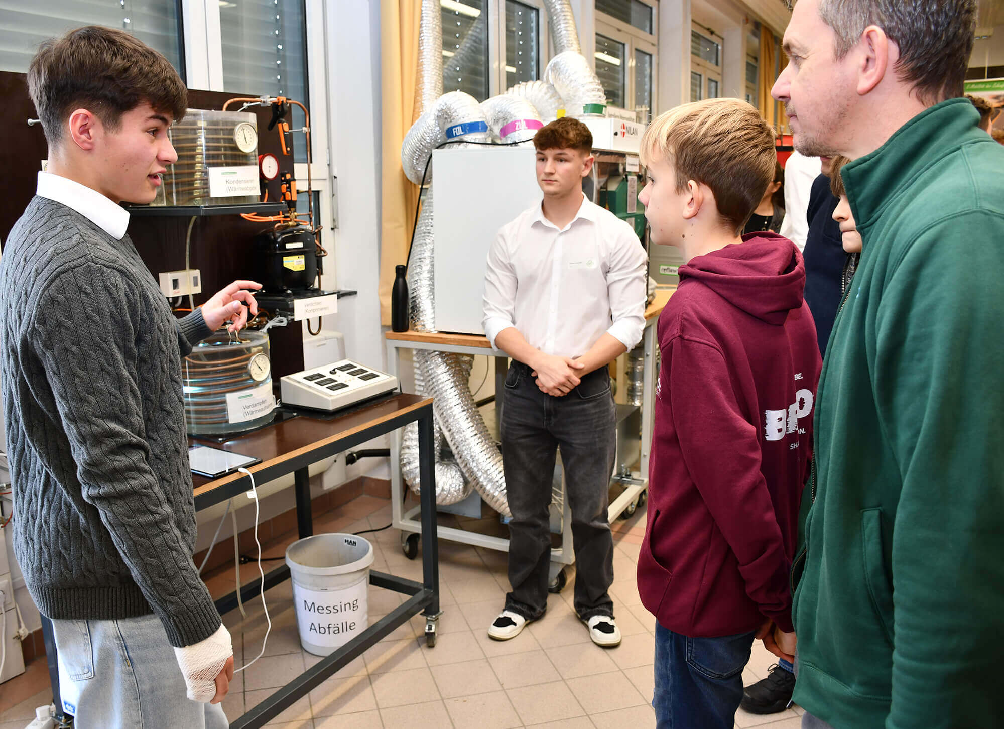 Junger Mann erklärt Laboraufbau einer Gruppe in technischer Einrichtung, Inhalt für Bildungsartikel im Prima Magazin.