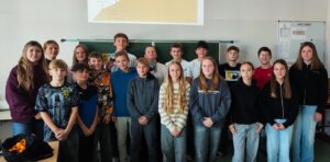 Eine Gruppe lächelnder Schüler vor einer Schultafel, thematisch passend zu einem regionalen Bildungsartikel.
