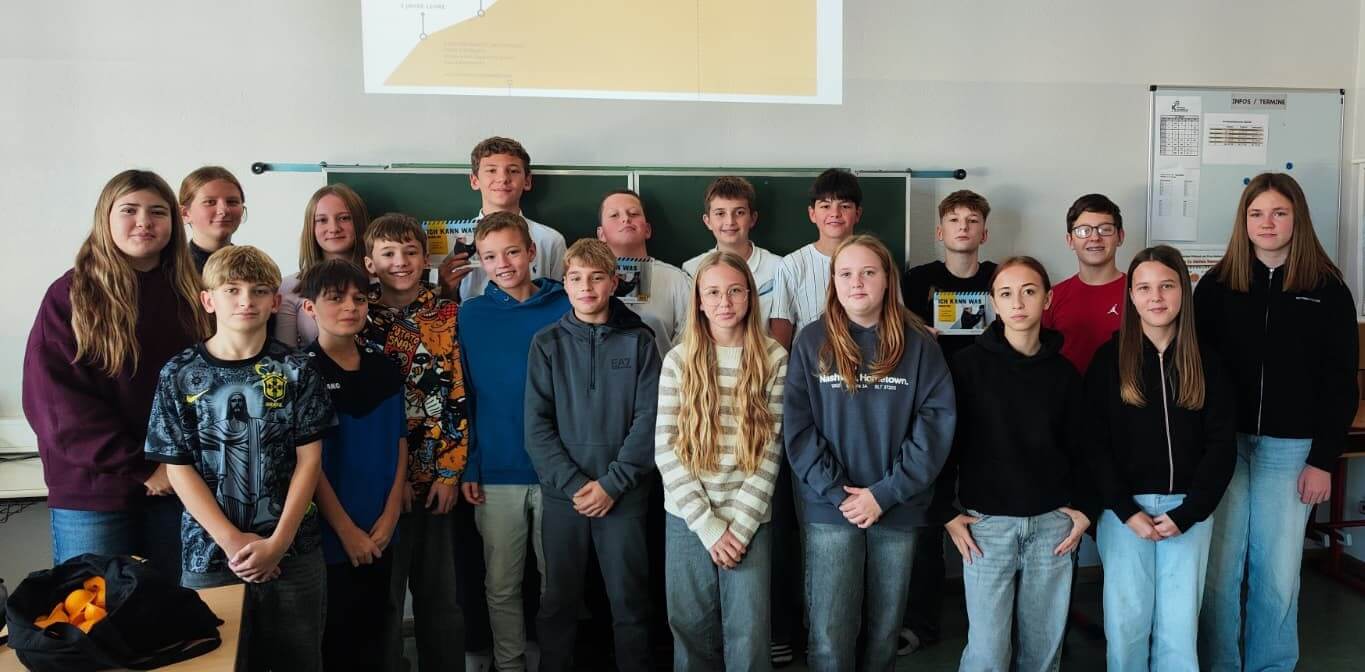 Eine Gruppe lächelnder Schüler vor einer Schultafel, thematisch passend zu einem regionalen Bildungsartikel.