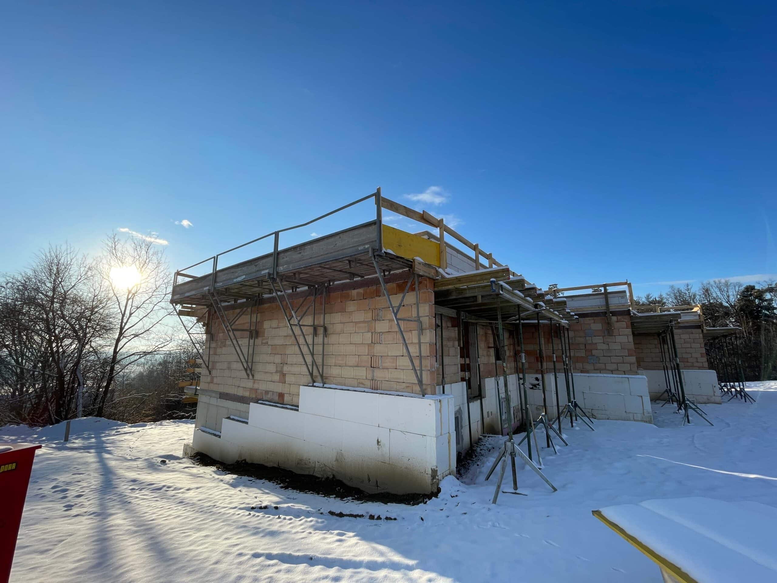 Rohbau im Schnee mit Gerüst bei Sonnenschein, eine winterliche Baustellenszene für das regionale Prima Magazin.
