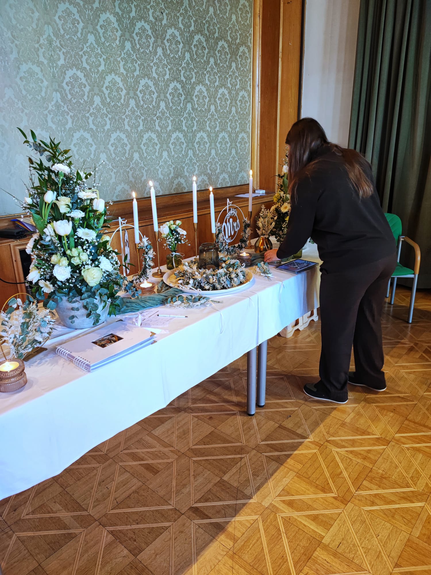 Eine Frau arrangiert Blumendekoration auf einem festlichen Tisch; bezaubernde Details für eine Magazin-Reportage über Events.