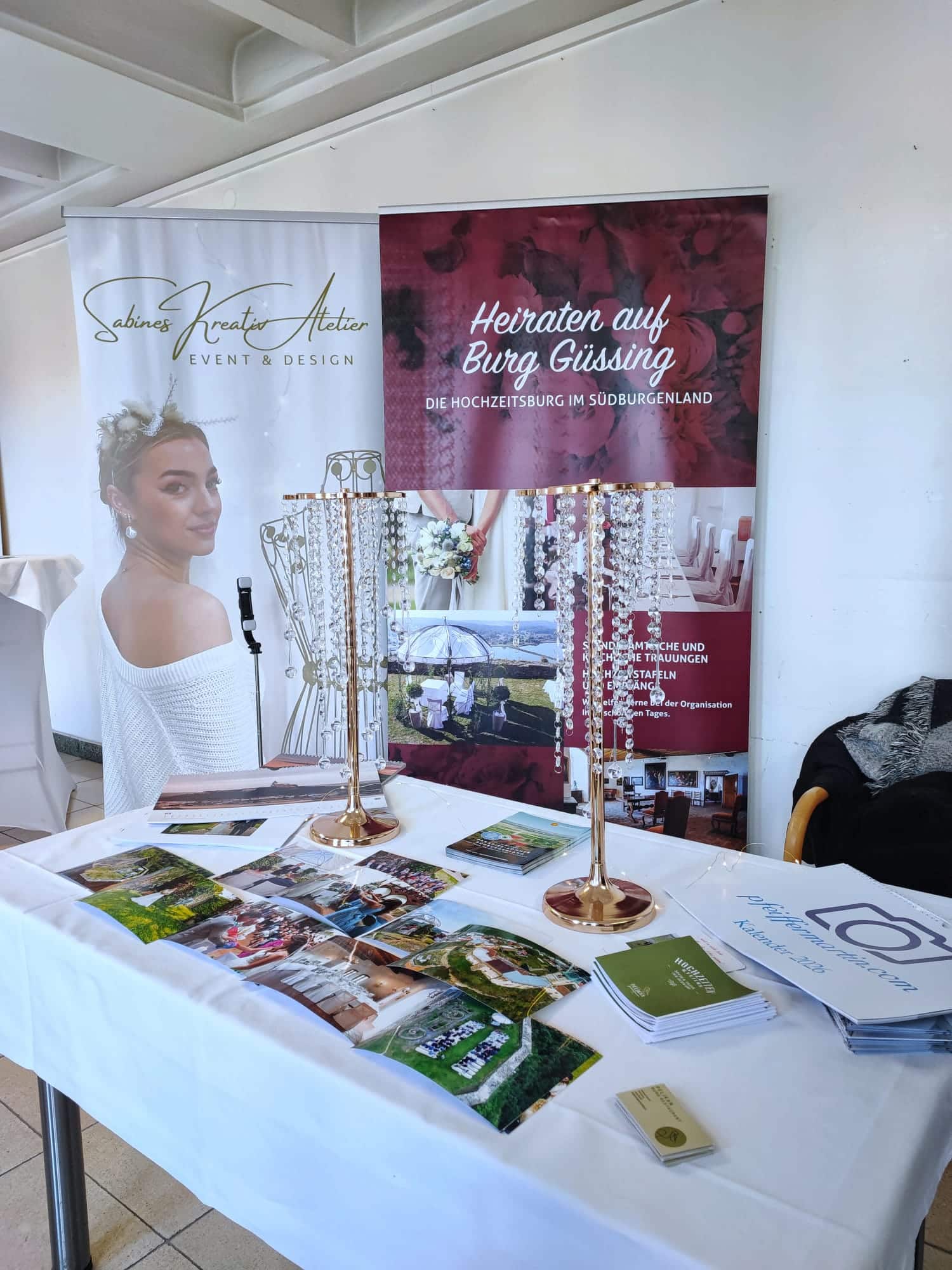 Messestand mit Werbematerial und Bannern für Hochzeit auf Burg Güssing, präsentiert von Sabines Kreativ Atelier.