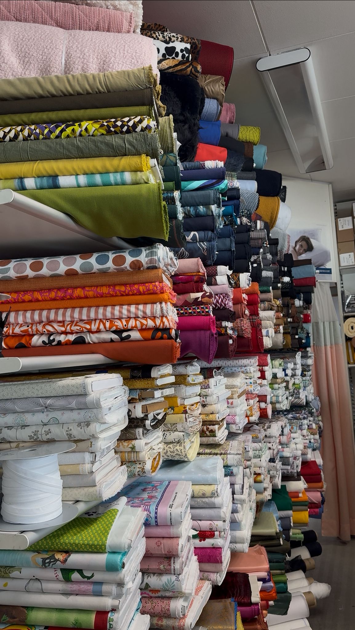 Stoffballen in leuchtenden Farben stapeln sich in einem textilen Fachgeschäft. Ideal für Kreative und Nähprojekte.