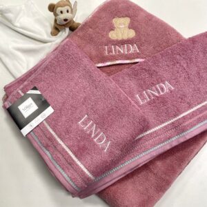 Personalisierte rosa Handtücher mit Namen Linda, verziert mit Teddybär-Stickerei, daneben ein kleines Kuscheltier.