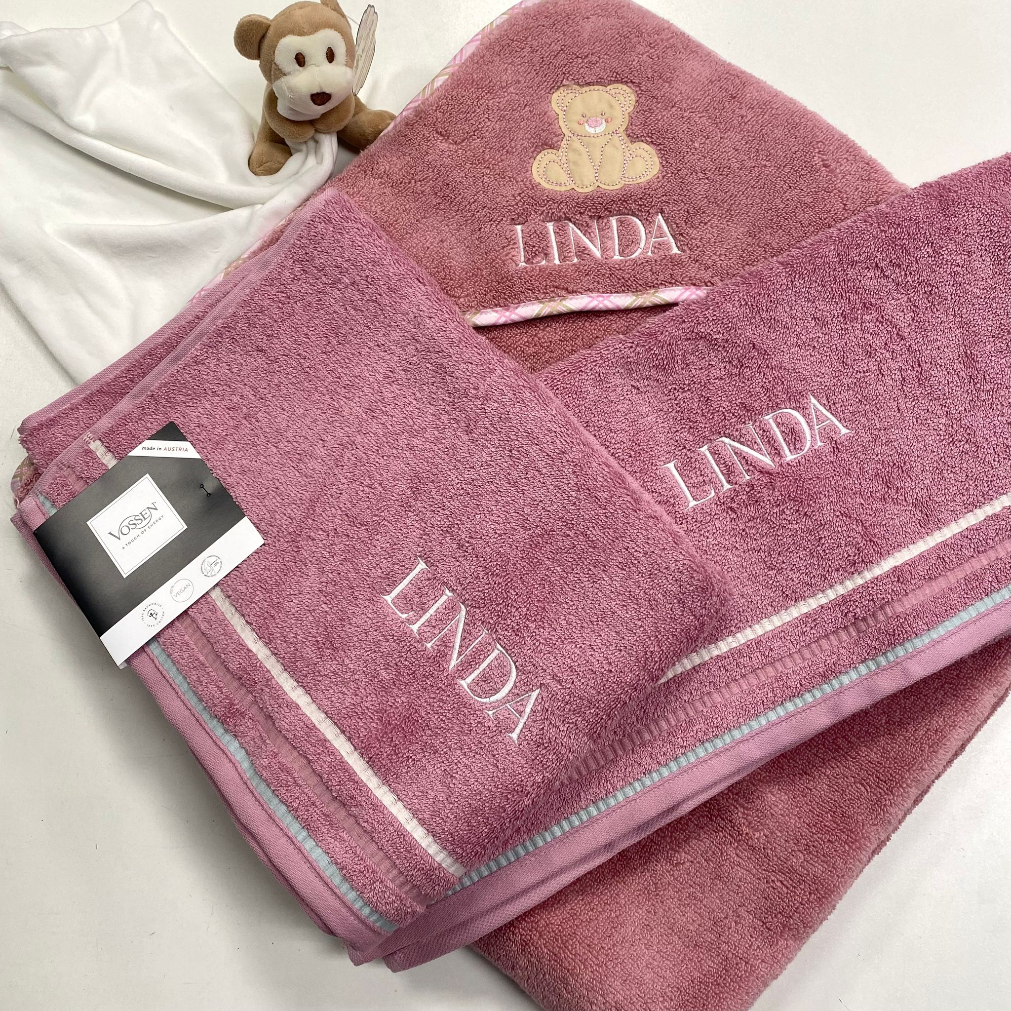 Personalisierte rosa Handtücher mit Namen Linda, verziert mit Teddybär-Stickerei, daneben ein kleines Kuscheltier.
