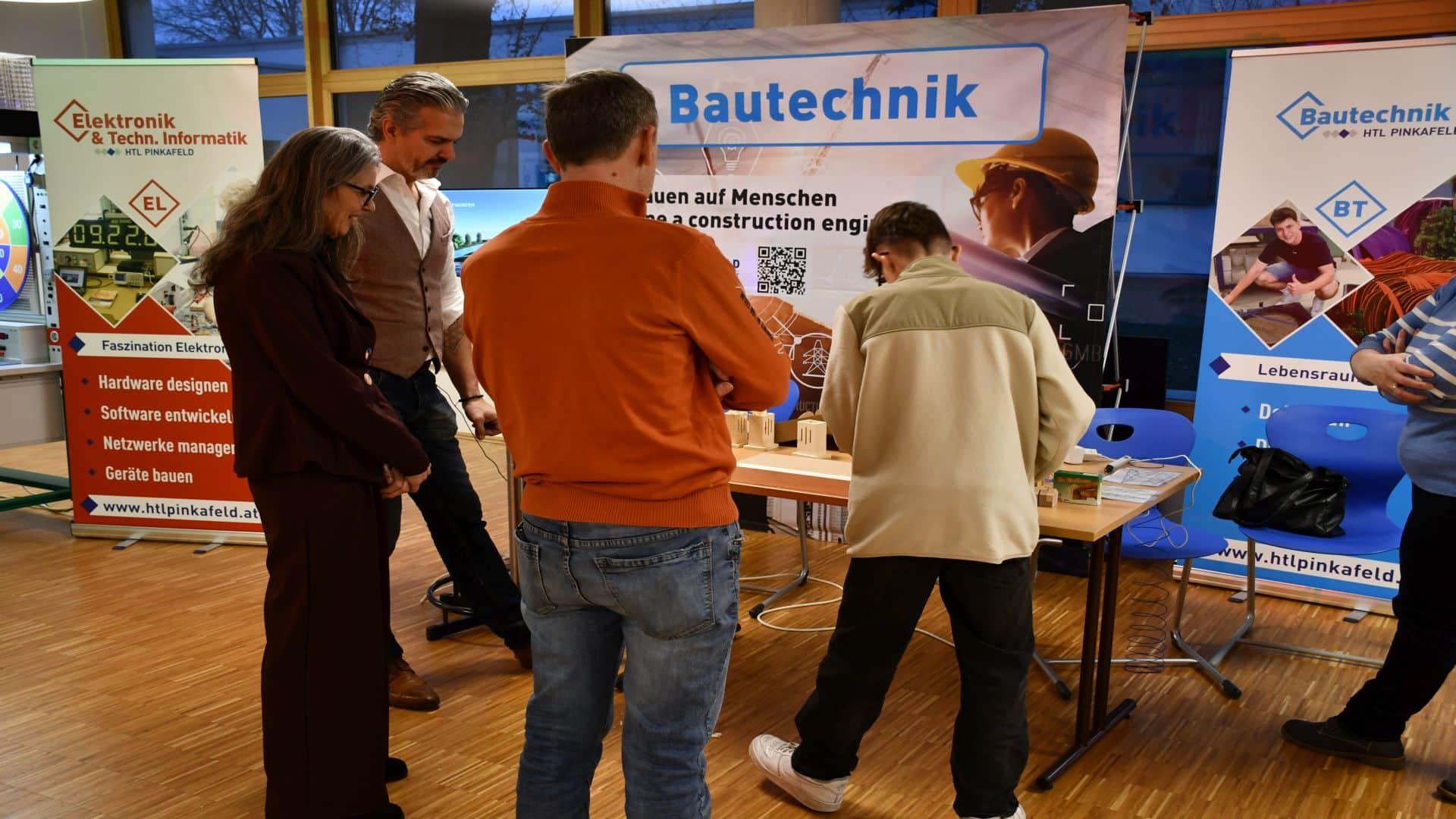Besucher informieren sich bei einem Stand über Elektronik und Bautechnik auf einer Messe, präsentiert von HTL Pinkafeld.