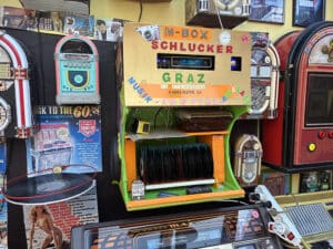 Bunte Jukebox-Ausstellung in Graz; Vintage Musikautomaten und Poster aus den 60ern, nostalgisches Flair im regionalen Fokus.