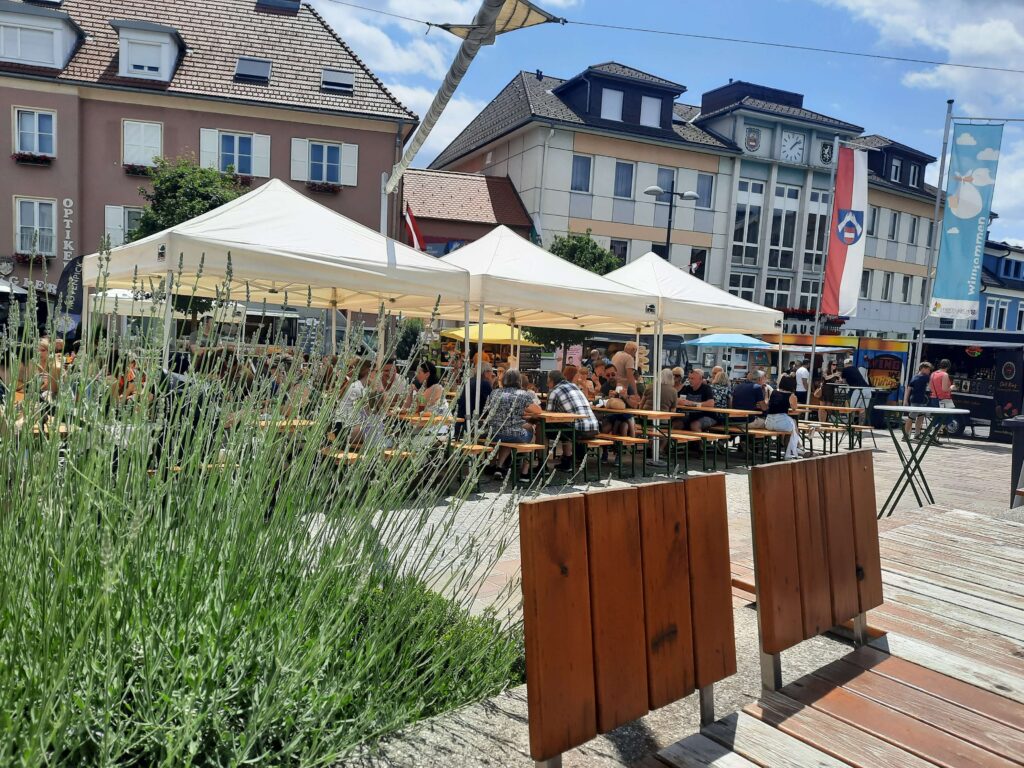 StreetFoodMarket 2025 - Fotos Stadtgemeinde Friedberg (2) Belebter Hauptplatz von Friedberg mit Besuchern unter weißen Zelten vor historischen Gebäuden