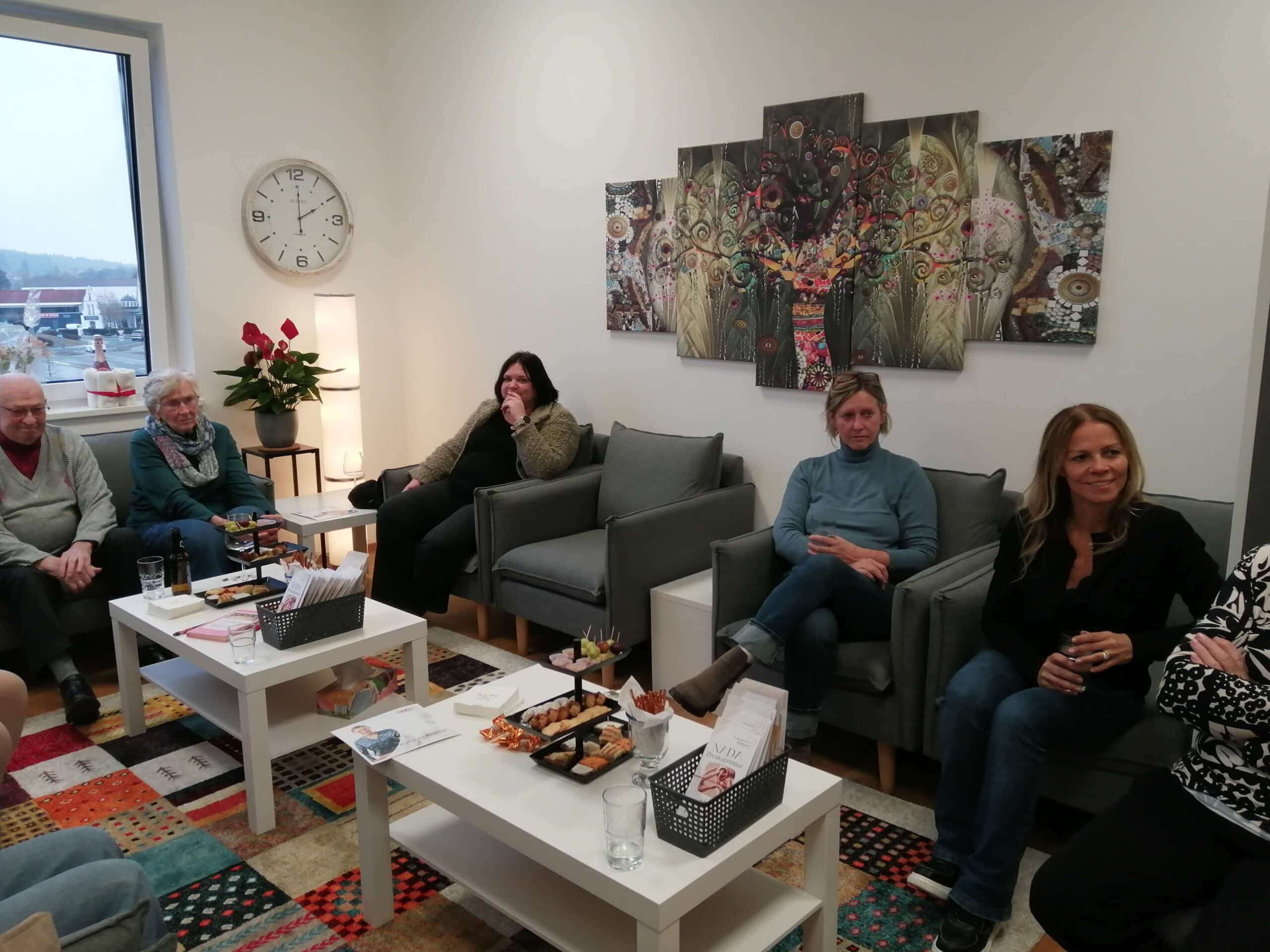 Eine Gruppe von Menschen im Gesprächsrunde bei Prima Magazin in einem gemütlichen Raum mit Snacks und Getränken.