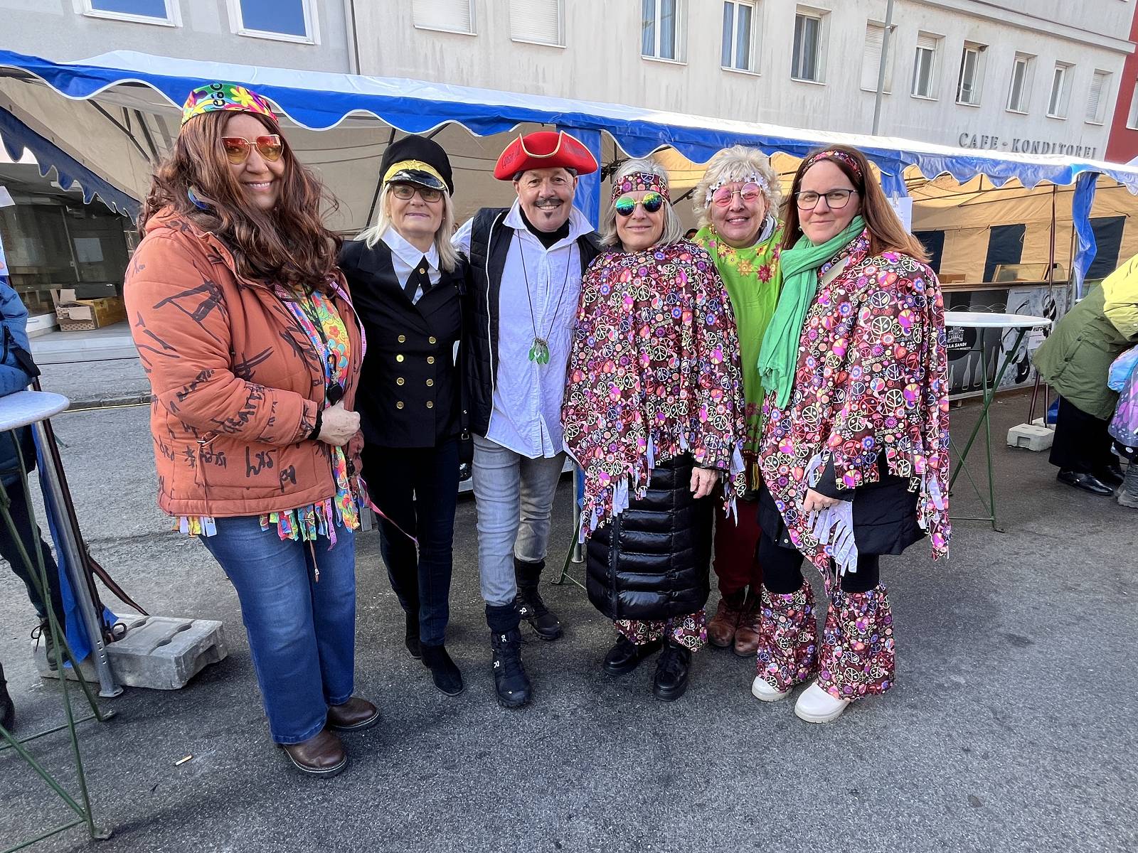 Gruppe von Menschen in bunten Kostümen, die auf einem Straßenfest fröhlich posieren, präsentiert im Prima Magazin.