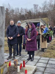 Menschen gedenken mit Kerzen und Blumen an einer Gedenkstätte im Freien, passend zum regionalen Magazin-Thema von Prima Magazin.