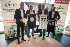 Gruppenfoto von vier Männern bei einer Fußballveranstaltung des Burgenländischen Fußballverbands mit personalisierten Trikots.
