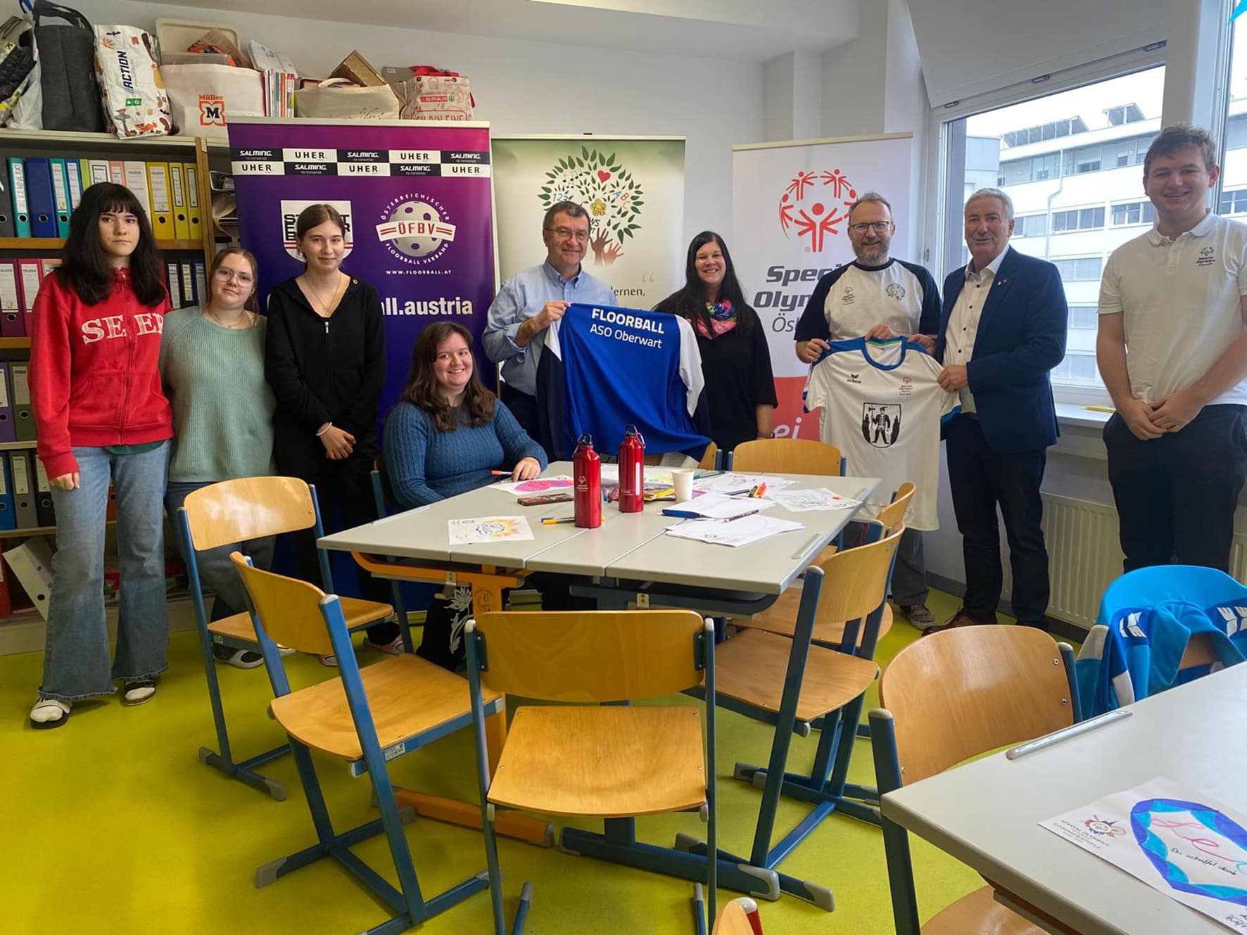 Gruppe bei einer Trikotübergabe im Klassenzimmer, Zusammenarbeit zwischen einem örtlichen Verein und Special Olympics Österreich.