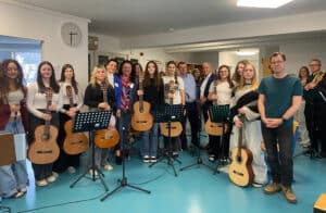 Gruppe junger Musiker mit Gitarren und Notenständern bei einer Musikveranstaltung im Prima Magazin-Büro.