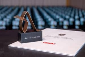 Auszeichnung Austriacus 2025 auf einem Tisch vor unscharfem Hintergrund, symbolisiert Exzellenz im regionalen Qualitätsjournalismus.