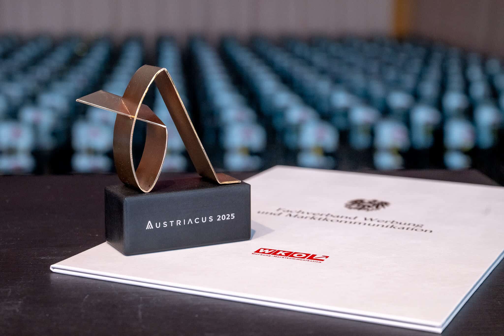 Auszeichnung Austriacus 2025 auf einem Tisch vor unscharfem Hintergrund, symbolisiert Exzellenz im regionalen Qualitätsjournalismus.